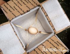 an egg is in a box with string wrapped around it and on top of some cardboard