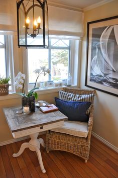 a room with a table, chair and lamp in it next to two pictures on the wall