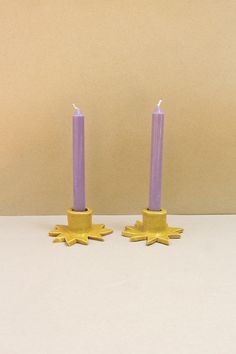 two purple candles sitting next to each other on top of a white table with gold stars