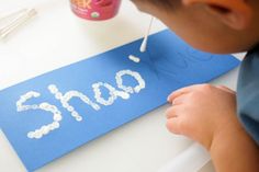 a young boy is painting the numbers on a blue piece of paper with white crayons