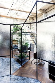 an office with glass walls and plants in the center, surrounded by wooden flooring