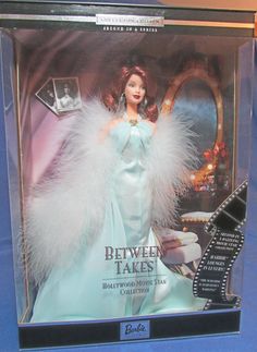 a barbie doll in a glass case on a blue table with a black and white film strip