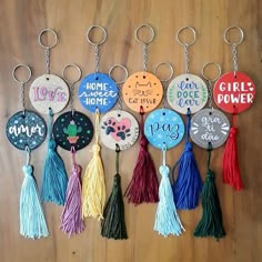 a bunch of key chains that have different designs and words on them with tassels