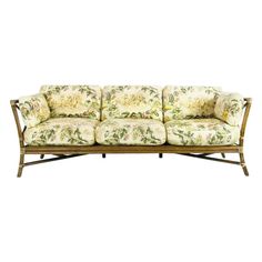 a couch with floral fabric on it and gold frame around the armrests, sitting in front of a white background