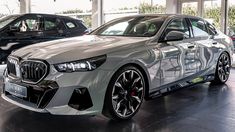 a silver car is parked in a showroom with other cars on display behind it