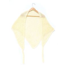 a white knitted shawl hanging on a wooden hanger