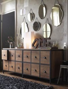 a dresser with several mirrors on the wall above it