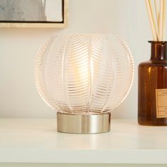 a glass ball shaped lamp sitting on top of a table next to a brown bottle