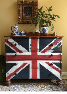 a british flag painted on an old dresser with potted plant in the corner next to it