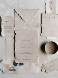 the wedding stationery is laid out on top of torn paper