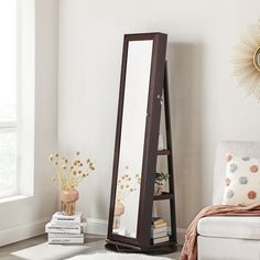 a tall mirror sitting on top of a floor next to a white chair in a living room