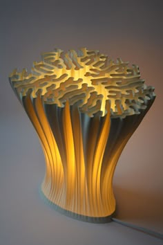 a lamp that is shaped like a tree with leaves on the top and sides, sitting on a white surface