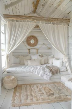 a bed with white sheets and pillows in a room next to a window, rugs on the floor