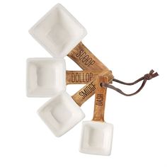 three square bowls with wooden handles and labels on them, hanging from a string against a white background