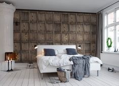 a bedroom with wood paneled walls and white bed in the center, surrounded by candles