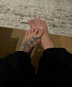 a woman's feet with tattoos on them and her hands resting on the floor