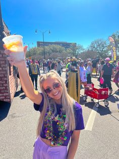 a woman holding up a plastic container with food in it while standing on the street