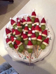 a platter filled with fruit covered in santa's hats on toothpicks