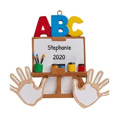 an ornament with two hands and paintbrushes in front of a sign that says abcc