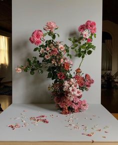 a vase filled with pink flowers sitting on top of a white table covered in confetti