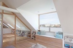 an attic bedroom with wooden floors and white walls, has large windows overlooking the city