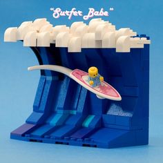 a lego model of a surfer riding a wave on his surfboard in front of a blue background