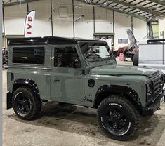 an army green land rover vehicle parked in a garage