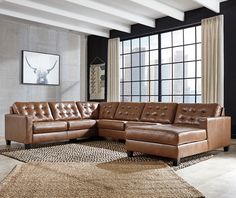 a brown leather sectional sofa sitting on top of a rug in front of a window