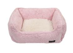 a pink dog bed with white fur on the bottom and side, in front of a white background