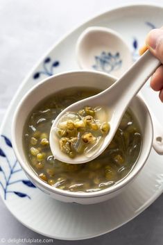 a spoon full of soup on top of a white plate