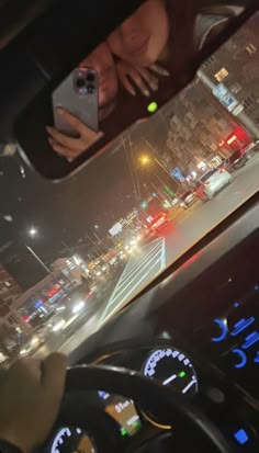 a woman is looking at her cell phone while driving in the street with traffic lights