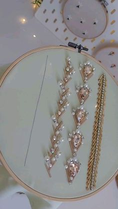 a white table topped with lots of different types of brooches and earrings on top of it