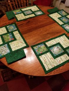 a wooden table topped with four place mats on top of a wooden table covered in green and white quilts