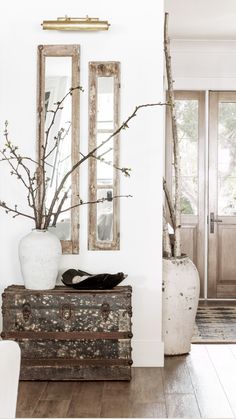 a white room with two mirrors and vases on the wall next to each other