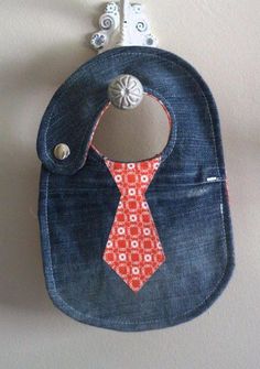 a denim pouch with an orange tie hanging from the side on a white wall next to a hook