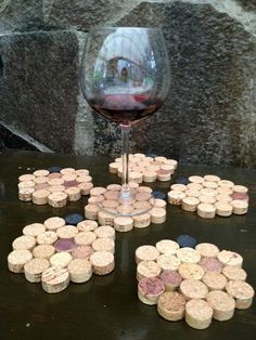 several wine corks are arranged on a table next to a glass of red wine