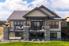 a large house with stone pillars on the front and back porches, surrounded by lush green grass