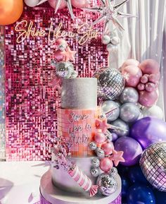 a pink and silver birthday cake surrounded by balloons