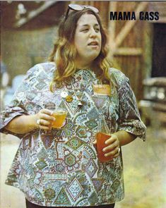 a woman holding a glass of orange juice in her right hand and looking off to the side