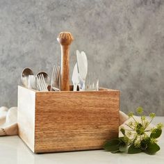 a wooden box filled with silverware and utensils on top of a table