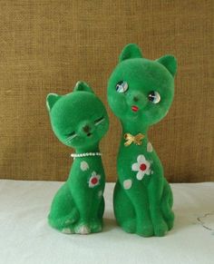 two green cat figurines sitting next to each other