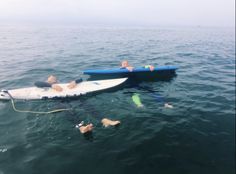 two people in the water with their surfboards and snorkels near them