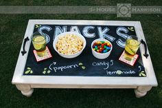 a chalkboard table with snacks and drinks on it in the shape of a sign