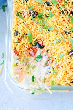 a casserole dish filled with cheese, black olives, tomatoes and cilantro