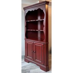 a red bookcase with two doors and shelves on the front, in an empty room