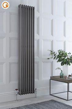 a white radiator in the corner of a room next to a table and potted plant