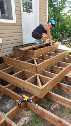 a woman in black shirt and blue cap working on wooden decking area with tools