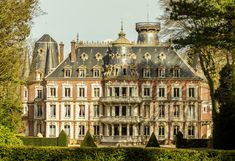 a large building with lots of windows in front of some trees and bushes around it