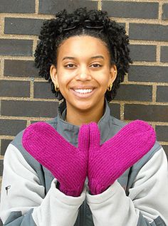 a woman with her hands in the shape of a heart, standing against a brick wall