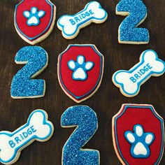 decorated cookies in the shape of dogs and bones on a table with blue glitters